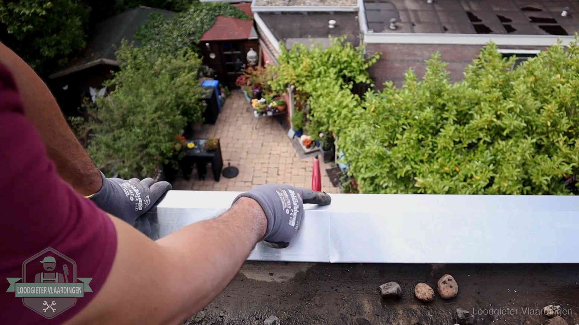 Vakman plaatst een daktrim op de dakrand van een woning in Vlaardingen
