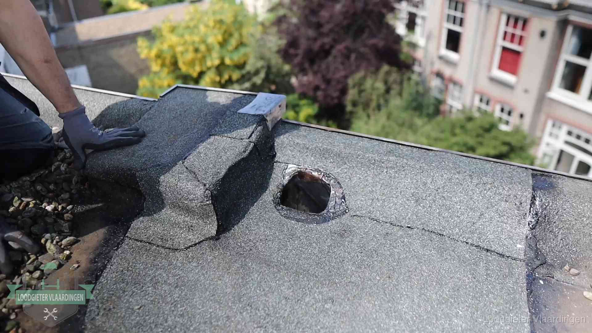Loodgieter inspecteert een beschadigd bitumen plat dak tijdens een daklekkage-inspectie in Vlaardingen