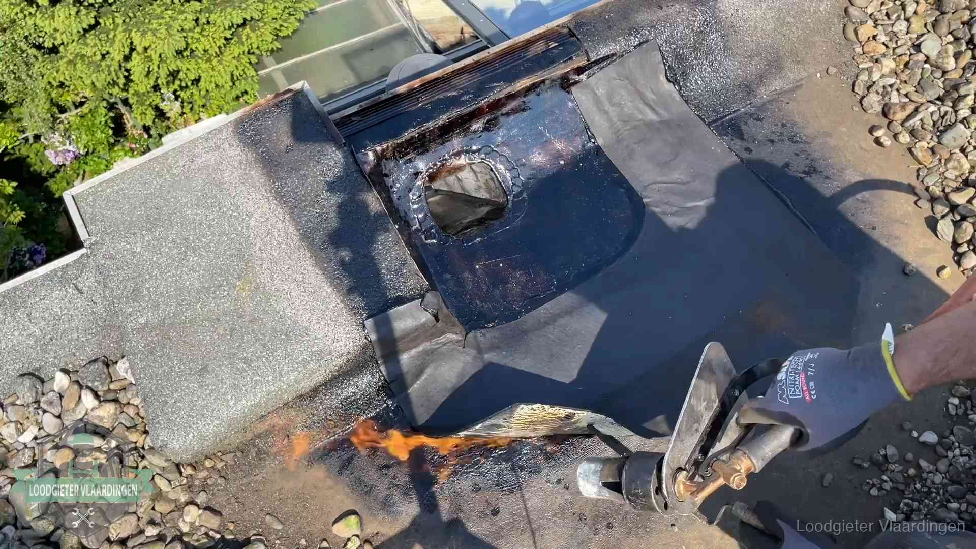 Dakdekker brandt bitumen rond een doorvoer tijdens een daklekkage-reparatie in Vlaardingen