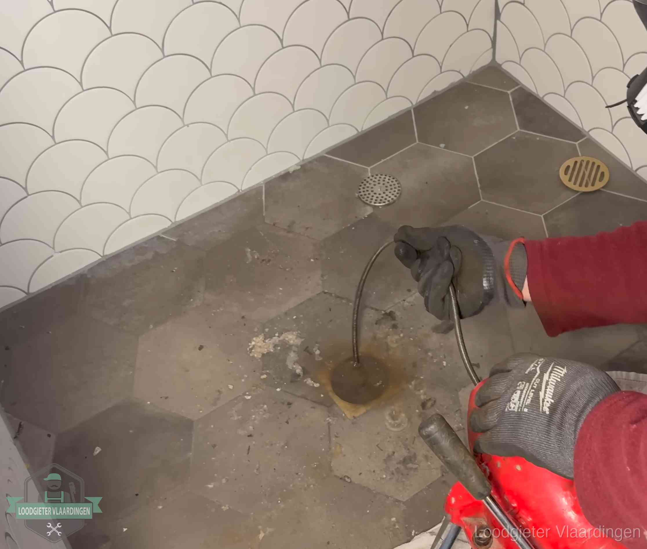 Ontstoppingsveer gaat in een geopend doucheputje in Vlaardingen waar het water omhoogkwam