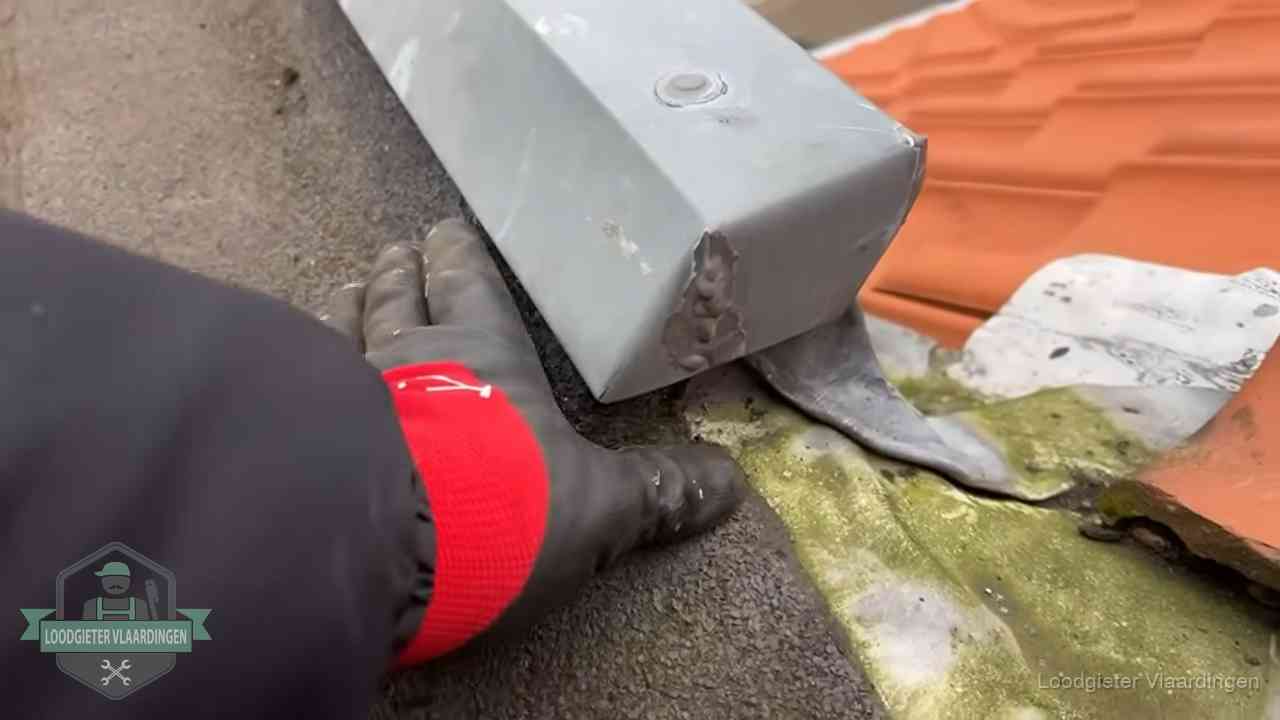 Controle van een zinken hemelwaterafvoer met loodslab bij dakpannen in Vlaardingen