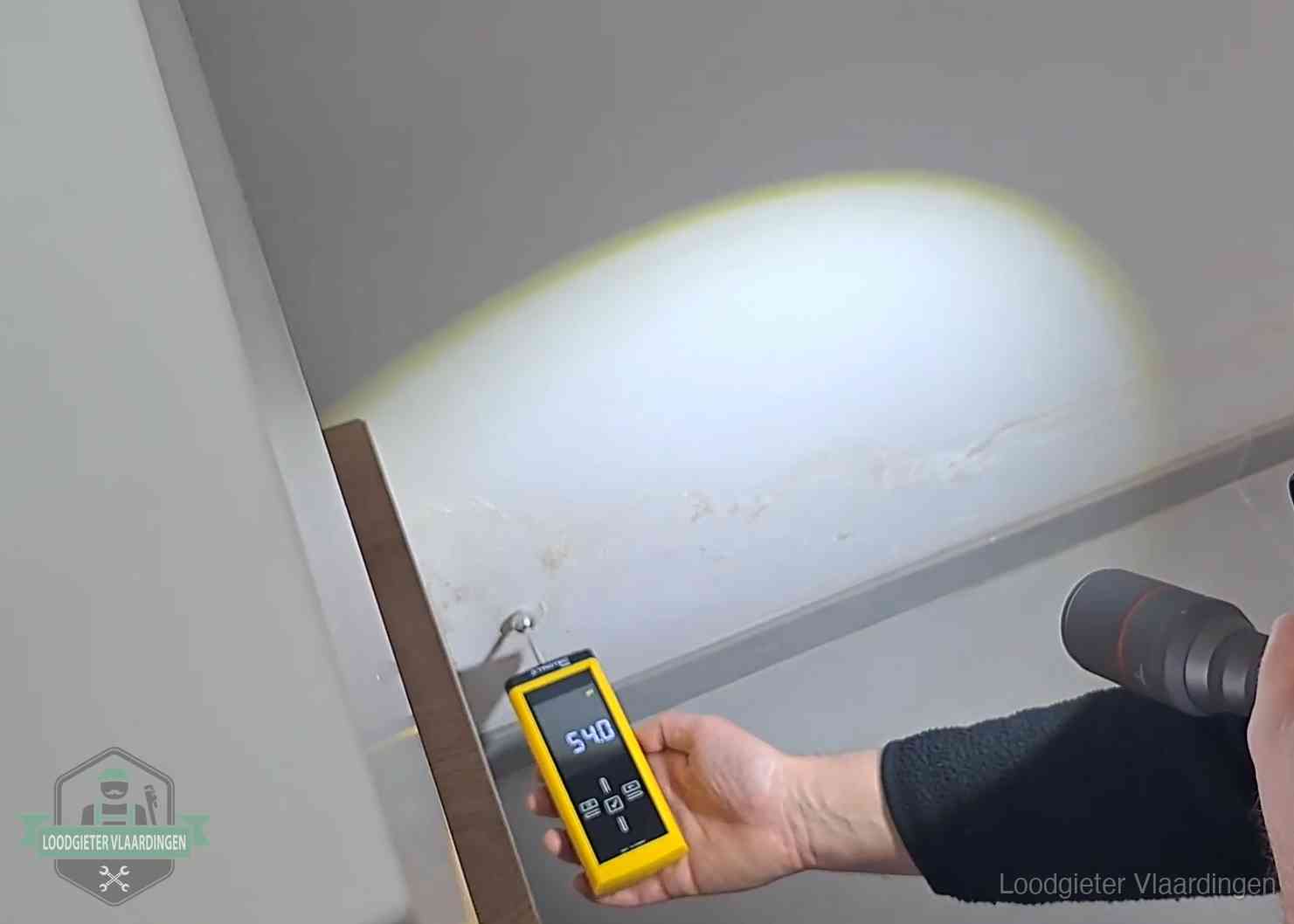 Vochtmeter tegen een natte wand met lekkagesporen in Vlaardingen