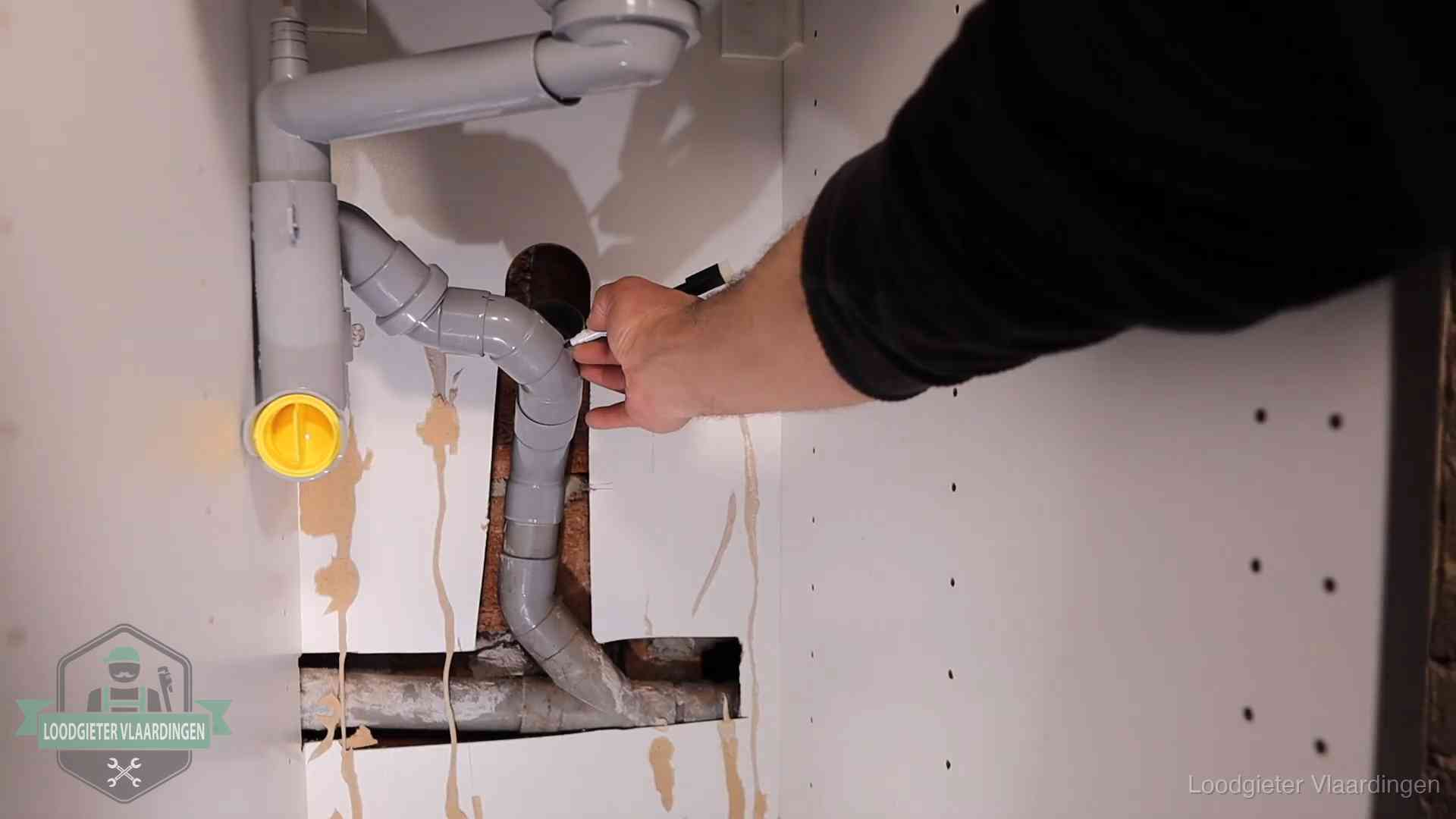 Loodgieter voor verhuurders en bedrijven in Vlaardingen Loodgieter markeert een pvc-afvoerbuis onder een gootsteen in Vlaardingen