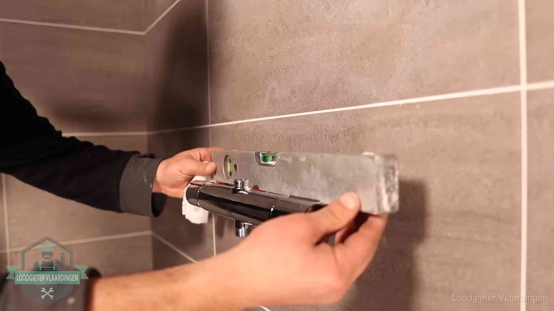 Loodgietersbedrijf voor sanitair in Vlaardingen Loodgieter lijnt een douchekraan uit met een waterpas in een woning in Vlaardingen