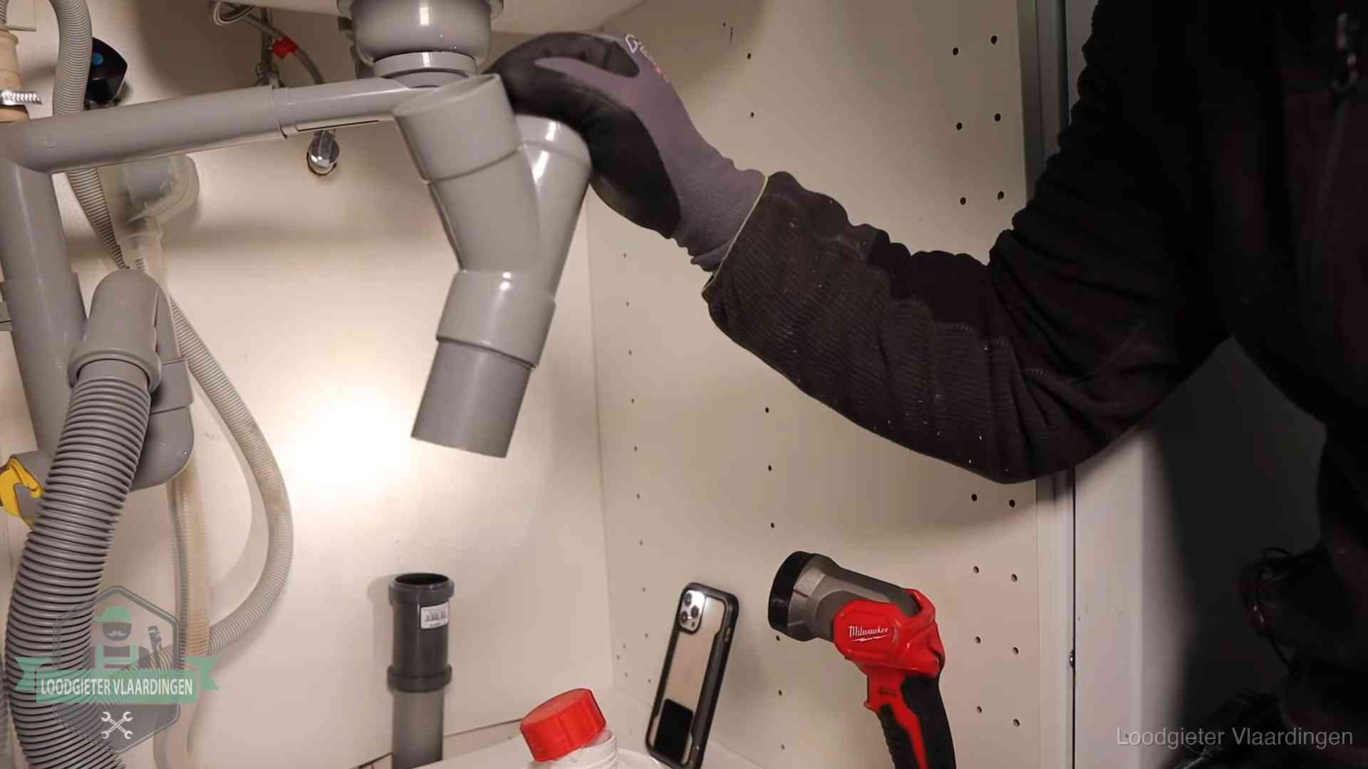 Loodgieter demonteert het sifon- en afvoerwerk onder een gootsteen in Vlaardingen bij stankklachten