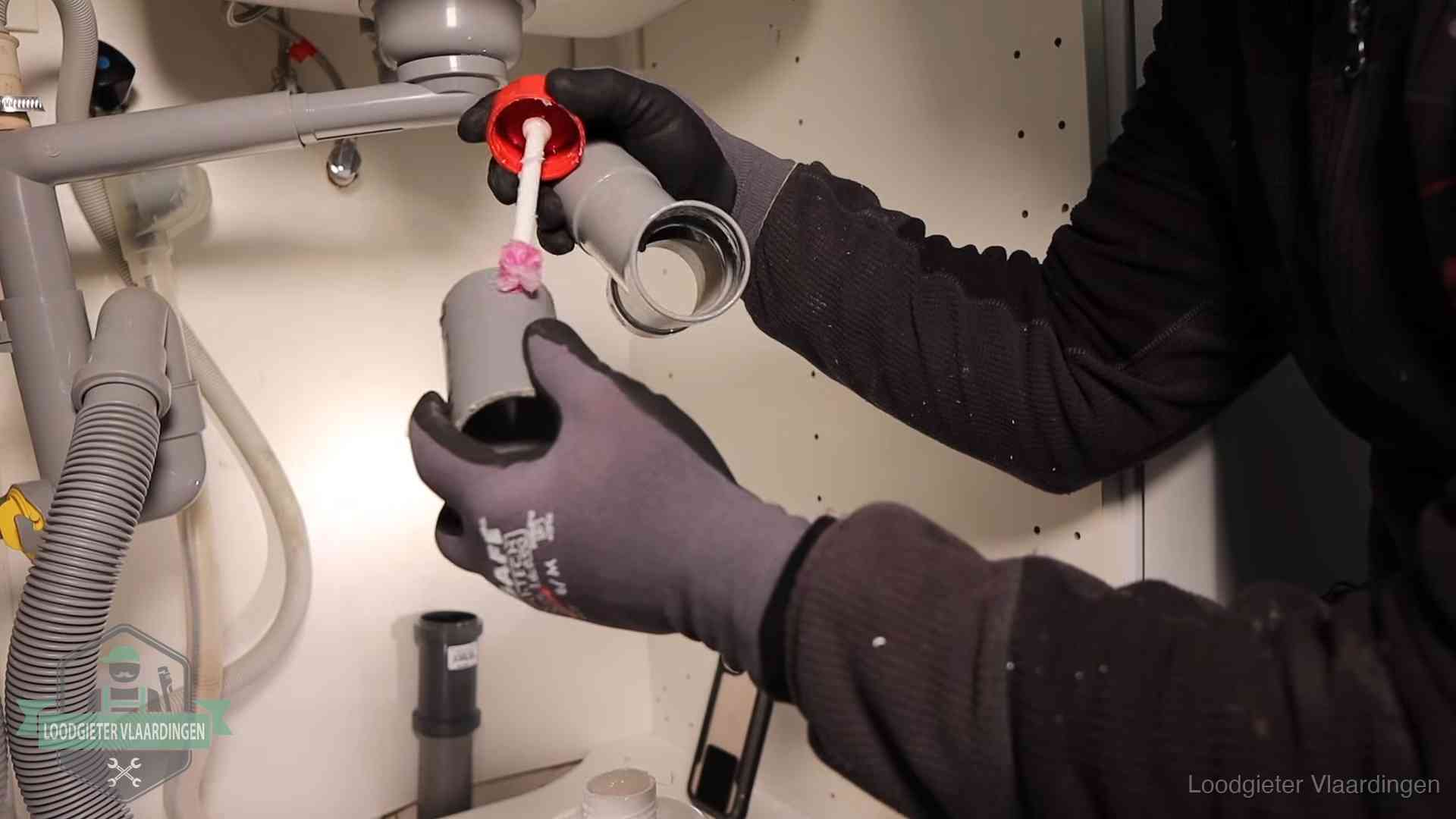 Loodgieter demonteert en reinigt de sifon onder een keukenkast in Vlaardingen