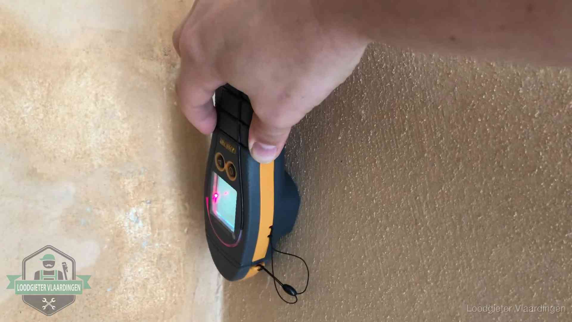 Vochtmeter tegen een muur met vochtplekken tijdens het opsporen van een daklekkage in Vlaardingen
