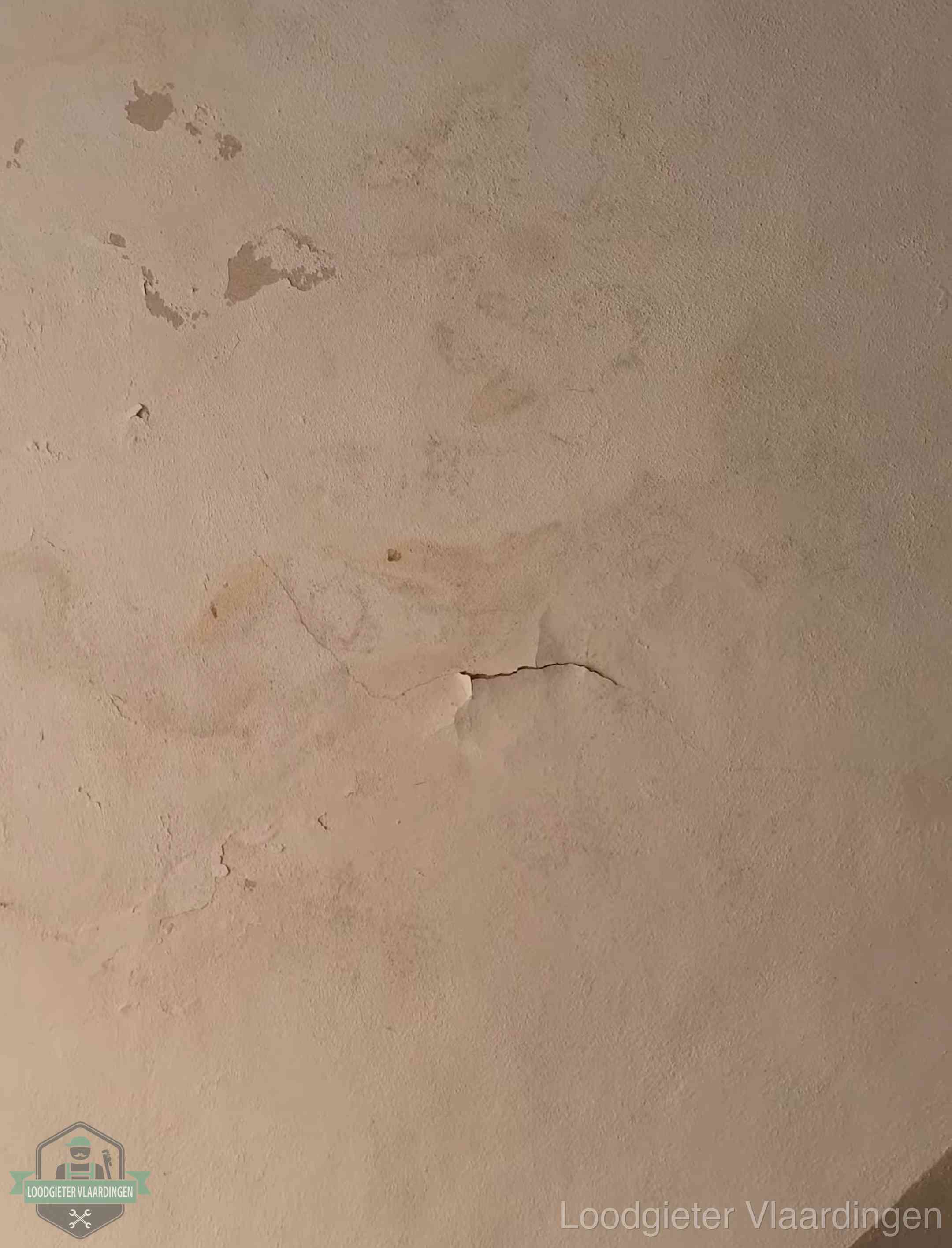 Vochtkringen en afbladderende verf op een plafond in Vlaardingen, schade voor het meetrapport en de verzekering